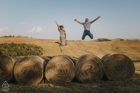 Pre-wedding engagement image-session in Crete Senesi, Tuscany with some leaps of love over the farmers wrapped hay bales