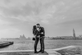 Venice fun-loving couple kissing in San Giorgio Island with the backdrop of St Mark and santa Maria della salute