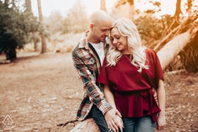 An engagement shoot took place at golden hour in Rowney Warren Woods, Hertfordshire UK. The couple sat on a fallen tree trunk, surrounded by soft and warm tones.
