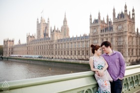 Engaged couple poses in front of a historic waterfront building in London, UK during a portrait session.