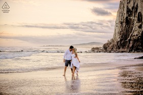 A couple poses for a pre-wedding photo session on the beautiful shores of Praia da Guarita in Torres, Rio Grande do Sul, surrounded by nature and engulfed in romance. 