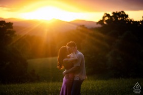 WPJA professional photographer captures a tender embrace between an engaged couple against the breathtaking backdrop of a setting sun and majestic mountain landscape in Asheville, NC.