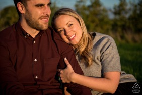 A soon-to-be-married couple exudes joy as they sit on a bench, soaking in the warm glow of the golden hour sun, in St Albans, Hertfordshire, captured by a WPJA photographer.