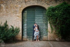 At Certosa di Pontignano in Siena, Tuscany, a WPJA photographer captures an intimate embrace as a couple stand before a weathered, green wooden door.