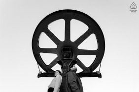 A couple in front of a big cable car wheel in the mountains in Font Romeu, France.