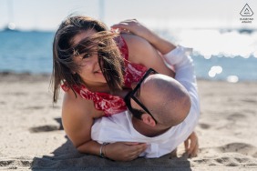 The couple rolls around in the sand on the beach of Saint Tropez, France.