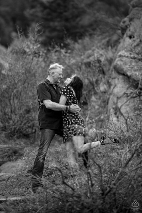 A newly engaged couple warmly embraces near the iconic Red Rocks Park and Amphitheater in Morrison, Colorado, celebrating their love at a scenic outdoor location they enjoy visiting together. 