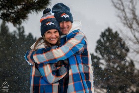 Dedicated Denver Broncos fans wear their team outfits for a snowy engagement portrait in Rocky Mountain National Park, Estes Park, Colorado, celebrating their love amidst the winter mountain landscape.