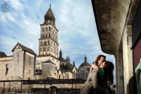 This couple embraces quietly while standing next to a historic building in Périgueux, Dordogne, enjoying a peaceful and intimate engagement portrait within the charming architectural heritage of southwestern France.