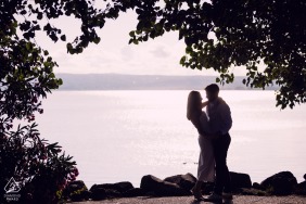 The dramatic silhouette of the couple is captured against the shimmering water at Lago di Bolsena, Italy, during a breathtaking sunset that emphasizes their romantic and lasting engagement bond.