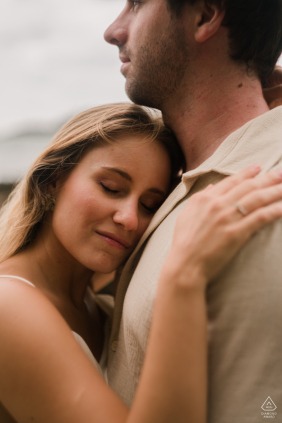 A happy couple shares a close and affectionate embrace during their outdoor engagement portrait session in the coastal city of Guarujá, São Paulo.