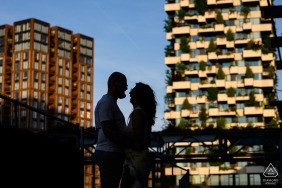 Standing in silhouette between two high-rise buildings in Eindhoven Strijp-S, Netherlands, the couple is outlined by evening light against the modern urban backdrop of the city at night.