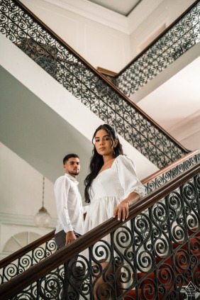 This elegant portrait features the couple posing on the grand historic staircases of the Palácio Deodoro in Alagoas, showcasing the classic architectural beauty of this unique Brazilian wedding venue.