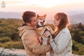 Sharing a tender embrace at golden hour with their dog in Beaujolais, Roche d'Ajou, France, the couple finds pure joy in a lighthearted interaction while surrounded by the stunning French countryside.