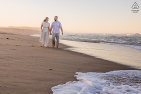 The couple walks barefoot along the shoreline at Newcomb Hollow Beach in Wellfleet, Massachusetts, letting the quiet rhythm of the ocean shape an unposed and intimate engagement portrait connection.