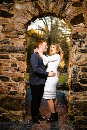 Framed by historic stone and golden light at Hunting Hill Mansion, Pennsylvania, the engaged couple is wrapped in laughter and ease during their elegant and scenic outdoor portrait session.