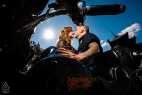 Wrapped in sun and steel, the couple shares an adventurous interaction while sitting atop a Harley Davidson motor street bike in Philadelphia, Pennsylvania, blending urban energy with their personal and romantic engagement connection.