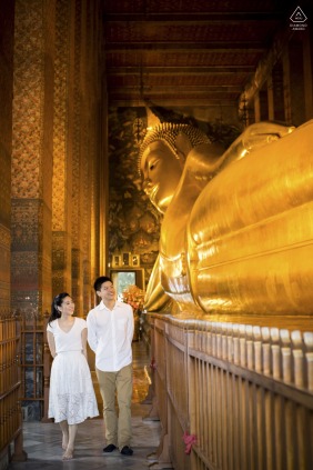 A loving portrait of the couple in Bangkok, Thailand, presents them against the gold art, their gentle smiles speaking to the affection they share on their special day.