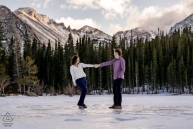 The couple dances atop the frozen surface of Bear Lake in Rocky Mountain National Park, Colorado, sharing a joyful spin on the ice with towering pines and snow-draped peaks circling their winter celebration.