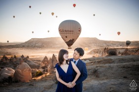 In Cappadocia, Turkey, a couple poses against the surreal landscapes of Goreme, Nevsehir, their pre-wedding session capturing the dramatic rock formations and expansive skies of this iconic region.