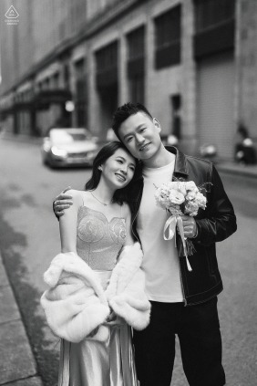 In Shanghai’s Bund, a couple leans into each other, her bouquet held by him as they pose for a straightforward engagement portrait with the city streets behind them.