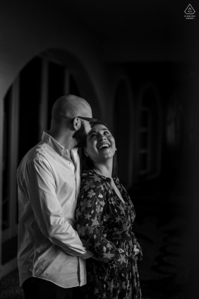 In Saint Tropez, France, a couple laughs together in a black-and-white portrait, the intimate pose set in a doorway evoking genuine emotion and warmth in the heart of this coastal town.