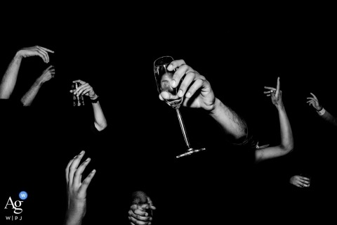 An image of hands toasting with glasses filled with beverages was captured during a celebratory night wedding party in Phu Quoc, Vietnam