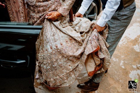 Birmingham, UK wedding reportage detail picture showing some Helping hands as the bride gets into an auto