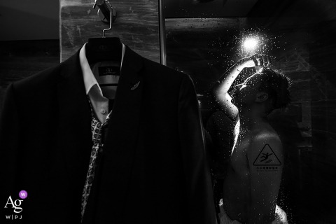 The groom made a creative statement on his wedding day, with his suit hanging in the foreground and his backlit silhouette in the shower Wenzhou, China creative wedding day image