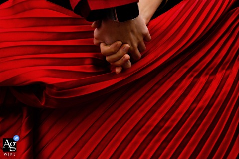 Chengdu, Sichuan fine art wedding picture showing the The bridegroom holding the bride's hand, and the dynamic red skirt forms a good background. I think it's a romantic moment