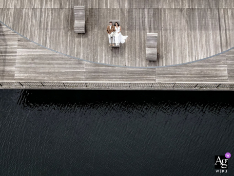 Best wedding venue photo from Switzerland as seen from above with a drone with bride and groom on wood deck by the water