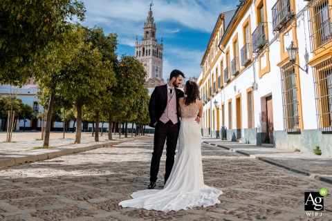 Romantic Sevilla wedding photo captures bride and groom on cobblestones, dress cascading beautifully.