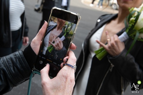 Inside Municipio di Suzzara, Mantova, Italy, the bride’s friend hopes to remember the ring, focusing her smartphone camera on the bride’s hand to highlight both the jewelry and their friendship.
