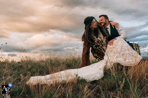 Bride playfully falls off rock while couple laughs during wedding portraits in Paradise Valley.