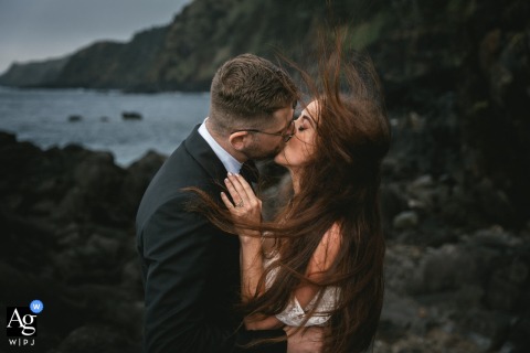 Couple shares their windy first kiss on Sao Miguel island, Azores, surrounded by natural beauty.