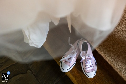 Close-up of bride's intricate lace dress and elegant white shoes at Rivervale Barn, Surrey.