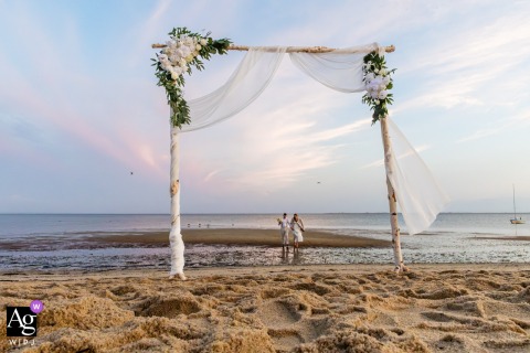 A dreamy pastel horizon frames a barefoot couple at their Cape Cod, Massachusetts, ceremony, surrounded by florals and sea breeze.