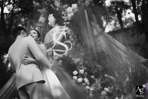 The couple tenderly embraces before a floral wedding arch at their villa in Shanghai, China.