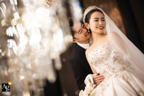 The groom embraces the bride tenderly under sparkling chandeliers at Hyatt Regency Chongming, Shanghai, China.