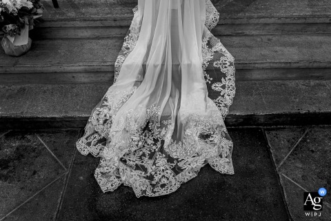 Black and white photo: bride’s dress elegantly draped on historic church stairs in Saint Georges d’Esperanche.