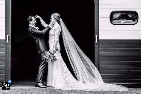 A humorous black and white shot of a couple in a framed doorway, during their photoshoot at the bride's mom's home in Zuid Holland, Netherlands.