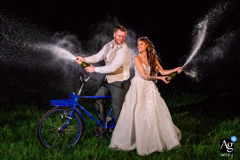 Bride and groom pop champagne, sitting on their party bike, at Zuid Holland, Netherlands celebration.