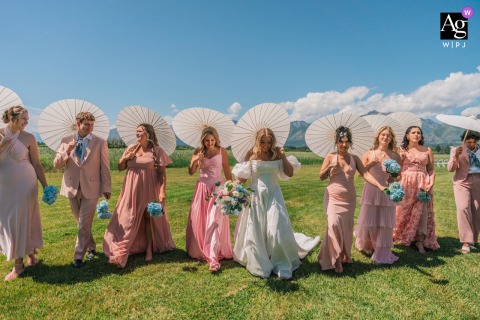 Montana bridesmaids walk with stylish umbrellas past Teller Wildlife Refuge, smiling together.
