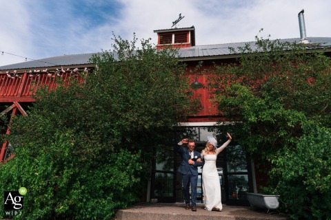 A scenic couple’s portrait features the newlyweds in front of the rustic buildings and natural landscapes of the Teller Wildlife Refuge in Bozeman, Montana, during their wedding day.
