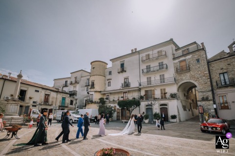 Bride and groom stroll through historic Roseto Valfortore, Italy; wedding attire swirling, cinematic and timeless atmosphere.
