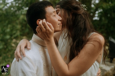 Bride kisses groom’s cheek lovingly at Château du Vivier, France, both smiling in wedding attire.
