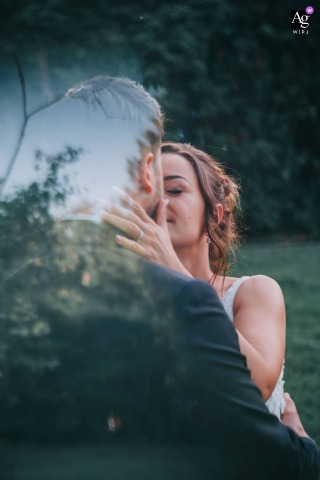 Bride and groom kiss in elegant wedding attire at Château de Clairvans, Jura, France, outdoors.
