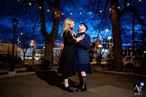 Two grooms dance joyfully in unique wedding attire at German Society Philadelphia, courtyard glowing after sunset.
