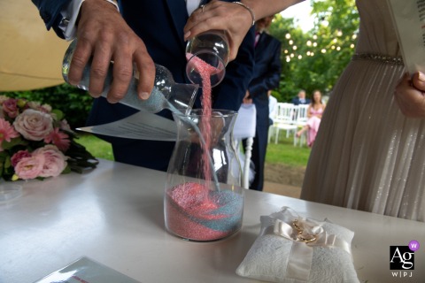 Detail of colored sand ceremony at Villa Eden, Mantova; newlyweds blend sands with motion blur.
