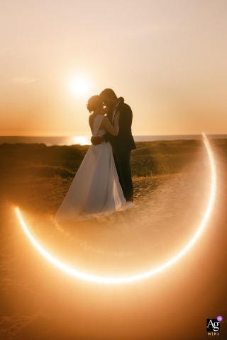 Bride and groom on dune, ring of fire sunset, ocean view, Les Sables d'Olonne, France.